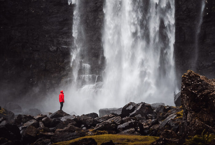 Person standing at Fossá waterfall