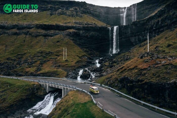 Camper driving next to waterfall