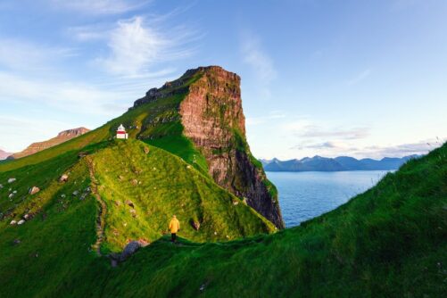 Man walking in mountains near lighthouse