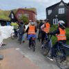 Cyclists between grass-roofed houses